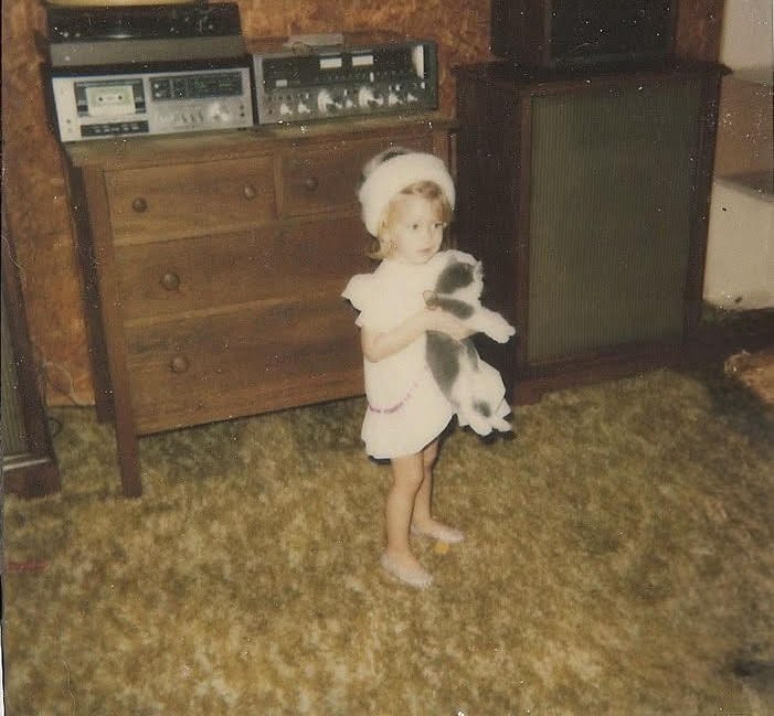 Shannon as a young girl, holding a grey and white cat